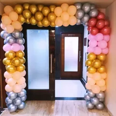 A classic balloon arch over a doorway using a mix of gold, silver, peach, pink, and red balloons. This is a versatile decoration for any kind of event.