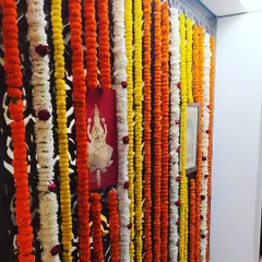 A simple and traditional wall decoration for a festival. I used strings of orange, yellow, and white marigolds to create a colorful backdrop against a decorative wall panel.