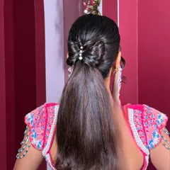 For a fun and glamorous Sangeet or cocktail party, I love creating chic styles like this sleek Barbie-inspired ponytail, finished with a delicate bow made of hair and pearls.