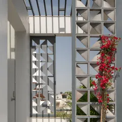 A view from the terrace, where the modular cement screen creates a play of light and shadow. The addition of bougainvillea adds a touch of color and nature, softening the concrete structure.