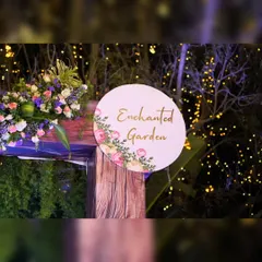 A close-up of an 'Enchanted Garden' sign, showing the beautiful calligraphy and floral details that add a touch of elegance to the event's entrance.