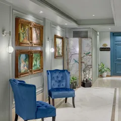 Another view of the refurbished foyer, showcasing how vintage art and vibrant blue chairs were reused to add personality. I love giving beloved pieces a new life, making each project sustainable and filled with personal history.