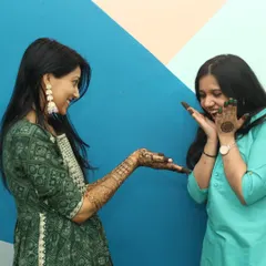 Capturing the fun interactions between family and friends is a key part of my pre-wedding photography. Here, two sisters share a laugh while admiring the fresh mehandi against a colorful backdrop.
