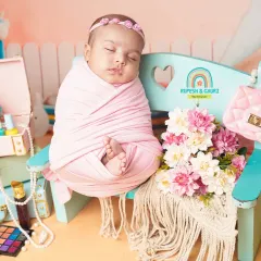 A stylish 2-month-old baby girl in a "little fashionista" setup, complete with a miniature handbag, makeup palette, and pearls.