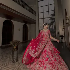 A bride in her magnificent red lehenga, captured in a way that shows off the full splendor of her outfit. The movement in the fabric adds a dynamic quality.