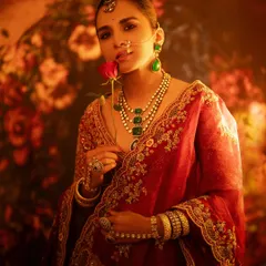 A fine art portrait with a painterly quality. The model holds a single red rose, and the warm, diffused lighting against a floral backdrop creates a romantic and timeless image.