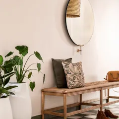The foyer of the Aqua Home makes a stunning first impression with its green and white marble checkerboard floor. A simple woven bench and a large round mirror create a welcoming and stylish entryway.