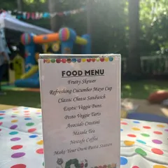 The food menu for this outdoor party included Fruity Skewers, Pesto Veggie Tarts, and a 'Make Your Own Pasta Station', all fitting the fun, colourful theme.
