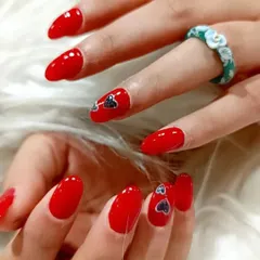 A vibrant red manicure gets a cute upgrade with tiny, shimmering heart decals on the accent nails.