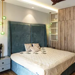 This bedroom is a perfect blend of comfort and style. A tall, upholstered headboard in a deep teal provides a sense of grandeur, while the green glass pendant lights add a pop of color and modern flair.