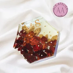 A hexagonal resin block preserving red and gold wedding flowers. The couple's initials, 'A & S', are featured in gold, creating a modern and personal keepsake to display on a desk or shelf.