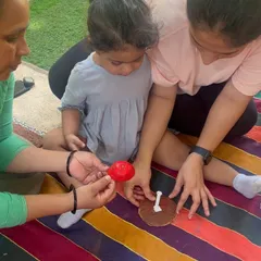 Here, a mother and grandmother work together with a child on a craft. My sessions welcome all caregivers, creating a supportive environment for the whole family to participate in the child's learning journey.