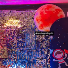 A close-up of the shimmering silver sequin backdrop with a red planet prop and a "Happy Birthday" neon sign. This combination of textures and light creates a dynamic and visually interesting focal point.
