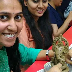 The pride in finishing your own piece of art is universal. A participant from a corporate event proudly shows off the detailed clay Ganesha she sculpted during our workshop.