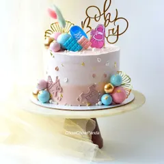 A "Oh Baby" baby shower cake. This Chocolate Truffle cake is decorated in gender-neutral pastels with cute baby-themed toppers like shoes and rattles.