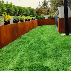 This rooftop lawn is bordered by a Corten steel planter. I ensure the turf remains healthy even in challenging environments like this, managing drainage and soil health for a perfect green carpet.