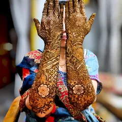 A bride showcasing her full-arm mehndi. The design is dense with traditional patterns, featuring beautiful rose motifs that stand out.
