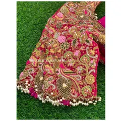 A close-up of the sleeve of the pink velvet bridal blouse. You can see the detailed zardozi work creating floral and peacock motifs, with delicate pearl tassels adding a finishing touch.