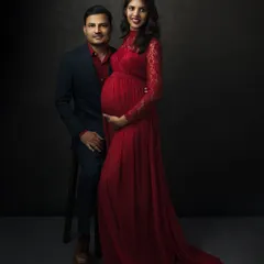 Together, you await the greatest adventure. This classic couple's maternity portrait in a stunning red lace gown is a testament to your shared journey and the love that builds a family.