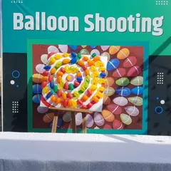 A professional balloon shooting game setup with a branded backdrop. This is a great way to add interactive fun to corporate events or product launches.