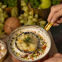From our 'RUMI' Diwali menu, a baked cheese dish in a copper pot, garnished with dill and pistachios, embodying festive indulgence.