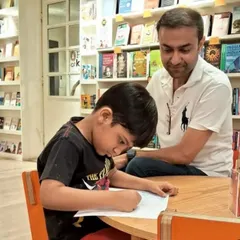 A father helps his son with a drawing activity. These quiet moments of collaboration and connection between parents and children are what our community is all about.