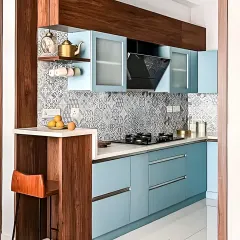 A wooden peninsula with a breakfast counter elegantly divides the kitchen from the adjoining area. The design combines warm wood tones with cool blue cabinets and a decorative tile backsplash.