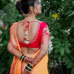 This portrait focuses on the stunning details of the bride's attire from behind. It showcases her elegant blouse design, traditional hairstyle with ambada pin, and the rich patterns of her mehndi.
