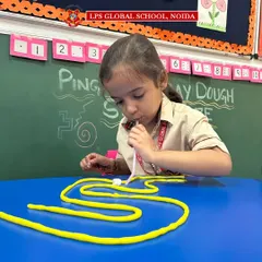 A young learner carefully blows a ping pong ball through a winding straw maze. This activity is one of the many ways we make skill-building an enjoyable and interactive experience.