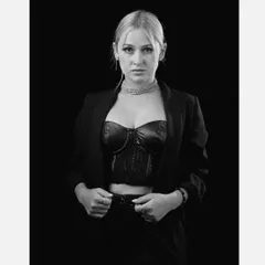 A strong and confident black and white portrait of a model in a blazer and corset top, showcasing a powerful and timeless look against a solid black background.