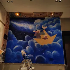 The finished dreamy night-sky mural, with two little adventurers in a paper boat, sailing on a sea of clouds under a starry sky. This is pure magic for a child's room.
