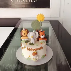 A sweet party animal cake featuring a lion, elephant, and tiger wearing party hats. The simple design and cute fondant figures are perfect for a little one's celebration.