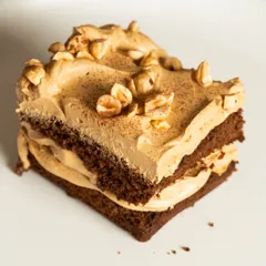 The perfect square of my Rum Soaked Dark Chocolate Traybake. You can see the distinct layers of rich chocolate sponge and light, fluffy coffee mousse, topped with crunchy hazelnuts.