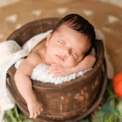 A rustic wooden bucket is a classic prop for newborn photography. It provides a cozy and secure space for the baby to rest in a natural, curled-up pose.