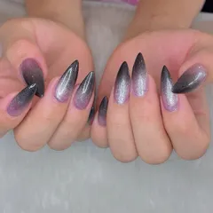 A dramatic ombré glitter effect on sharp stiletto nails. The color fades from a soft pink at the base to a deep, glittery black at the tips for a truly magical look.
