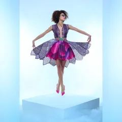 This image from a designer shoot highlights a structured, multi-layered dress. The lighting and pose are designed to showcase the unique cut and vibrant colors of the fabric, creating a visually striking fashion photograph.