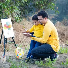 Painting together creates a special bond. This candid shot of a father and son enjoying our 'Little Artist' setup shows the gentle connection and shared joy that family sessions are all about.