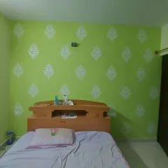 A fresh green bedroom wall decorated with a white damask stencil pattern, adding a touch of classic elegance to the space.