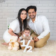 A perfect family shot from a half-birthday session. The baby sits in a basket, framed by his loving parents and a cute teddy bear.