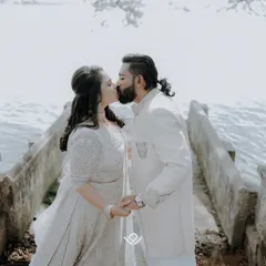 A romantic kiss shared by a couple by the water, a timeless and classic wedding photograph.