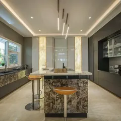 A luxurious kitchen designed for a culinary enthusiast, featuring dark cabinetry, a textured stone island, and dramatic pendant lighting. The large window allows for plenty of natural light, creating a perfect workspace.
