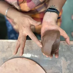 Before the work begins, there is the simple act of feeling the clay. This close-up shows a participant connecting with the material at the start of a corporate team building session.