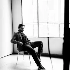 A relaxed and confident black and white portrait of an actor, shot with natural light in a studio. This has a classic, cinematic feel.