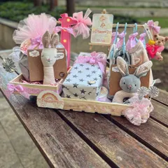 A full view of a custom hanger hamper I created for baby Vannya. This large tray includes a mini clothing rack, plush toys, and beautifully wrapped gifts, all in a soft pink and grey palette.