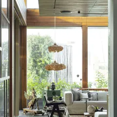 A view from the corridor into the sun-drenched conservatory. The design uses large glass panes and natural materials to blur the boundary between inside and out, creating a serene retreat within the home.