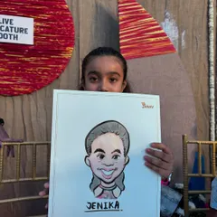 A young girl peeking over her freshly drawn caricature at a live event booth. These on-the-spot drawings are always a highlight for kids at parties.