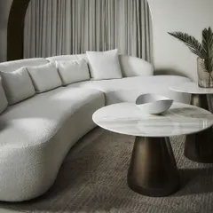 The Poet Sofa in a pristine white bouclé fabric, paired with our Cone Round Coffee Tables. The combination of the sofa's soft, curved form and the tables' sculptural marble tops creates a look of pure, understated luxury and modern elegance.