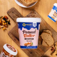 A top-down flat lay of Quantum Nutrition's peanut butter, surrounded by its ingredients like nuts and bread. This styling connects the product to a healthy, wholesome lifestyle.