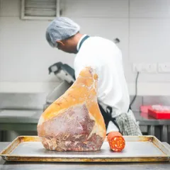 A look inside our butchery, where precision and responsibility meet. Here, a chef prepares a large leg of cured ham, a process that requires skill, patience, and a deep respect for the ingredient.