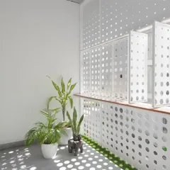 A detail of the white perforated screen, which acts as a modern interpretation of the traditional jali. It allows for ventilation and filtered light, crucial for the urban context.